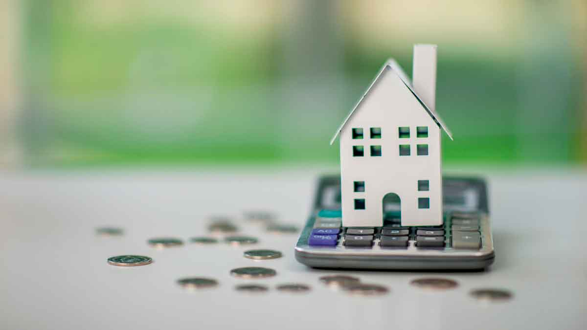 Casa en miniatura sobre calculadora con monedas, símbolo del euríbor y su impacto en hipotecas variables
