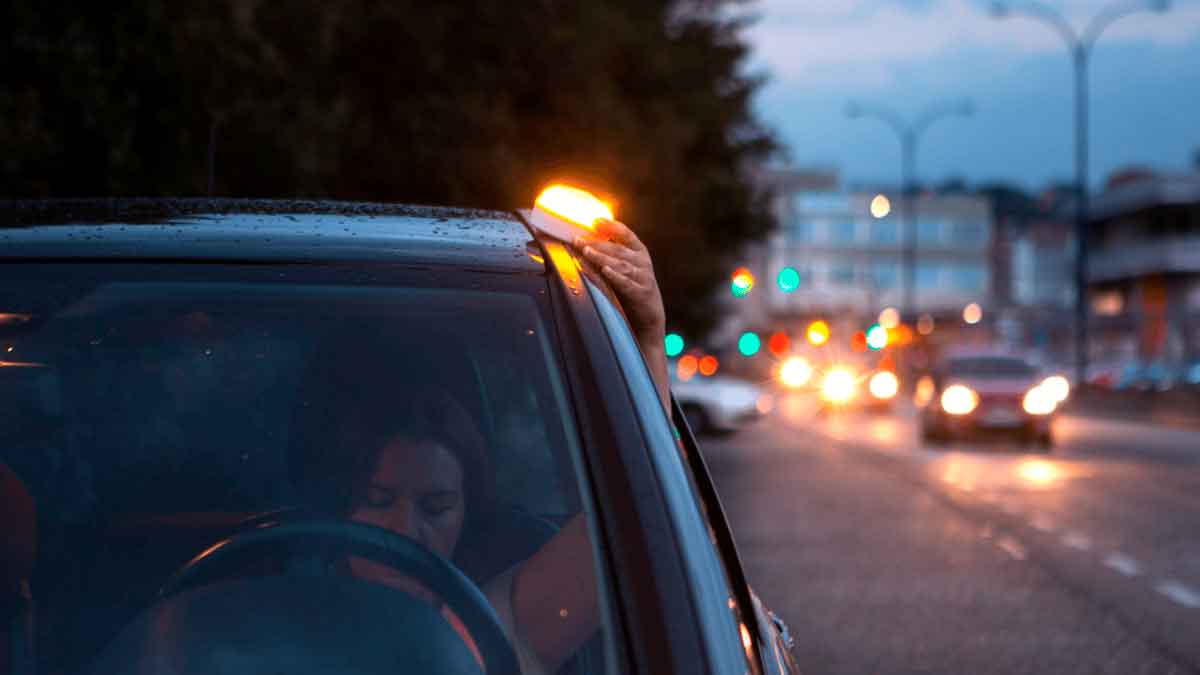 Conductor colocando luz de emergencia V16 homologada en coche según normativa DGT 2026