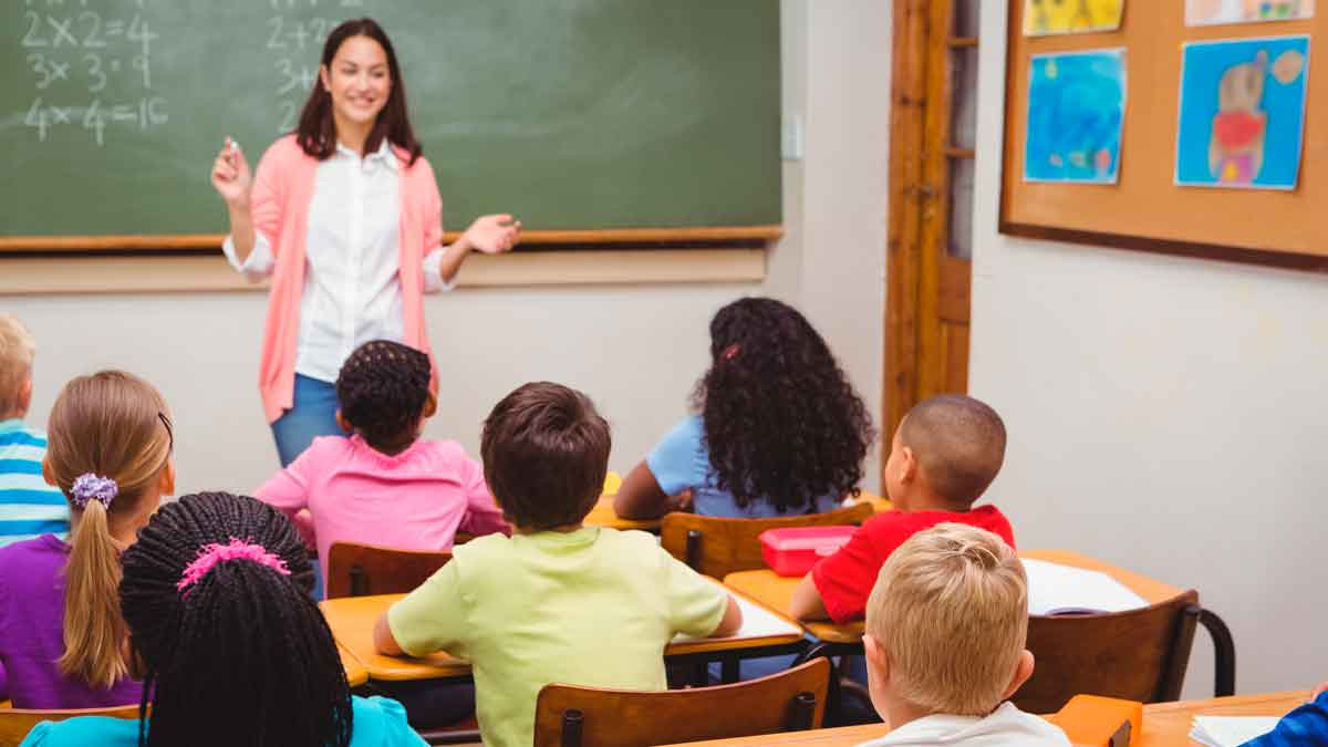 Maestra de Primaria explicando matemáticas en clase con niños en el aula