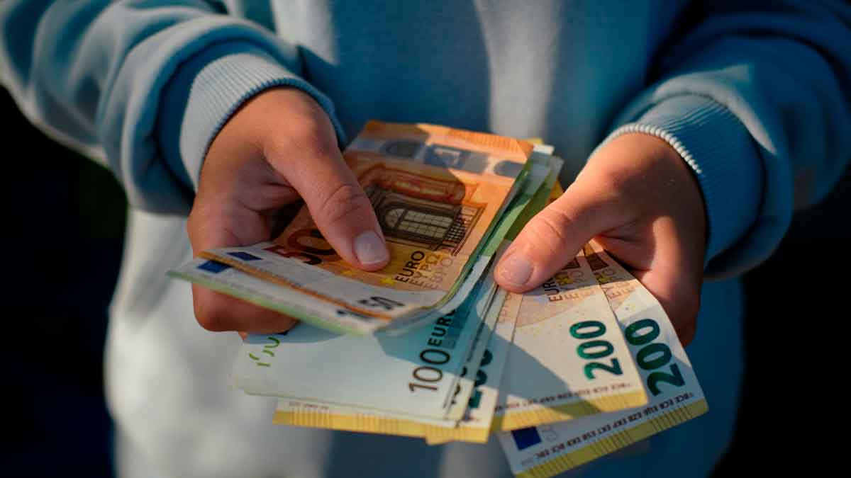 Persona contando billetes de euro para ilustrar cuánto paro queda con un sueldo de 1.500 euros, según el SEPE
