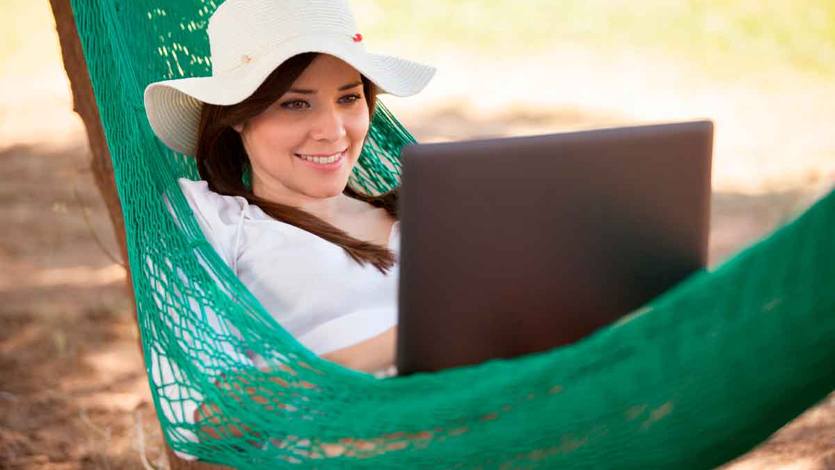 Mujer teletrabajando con portátil desde una hamaca al aire libre