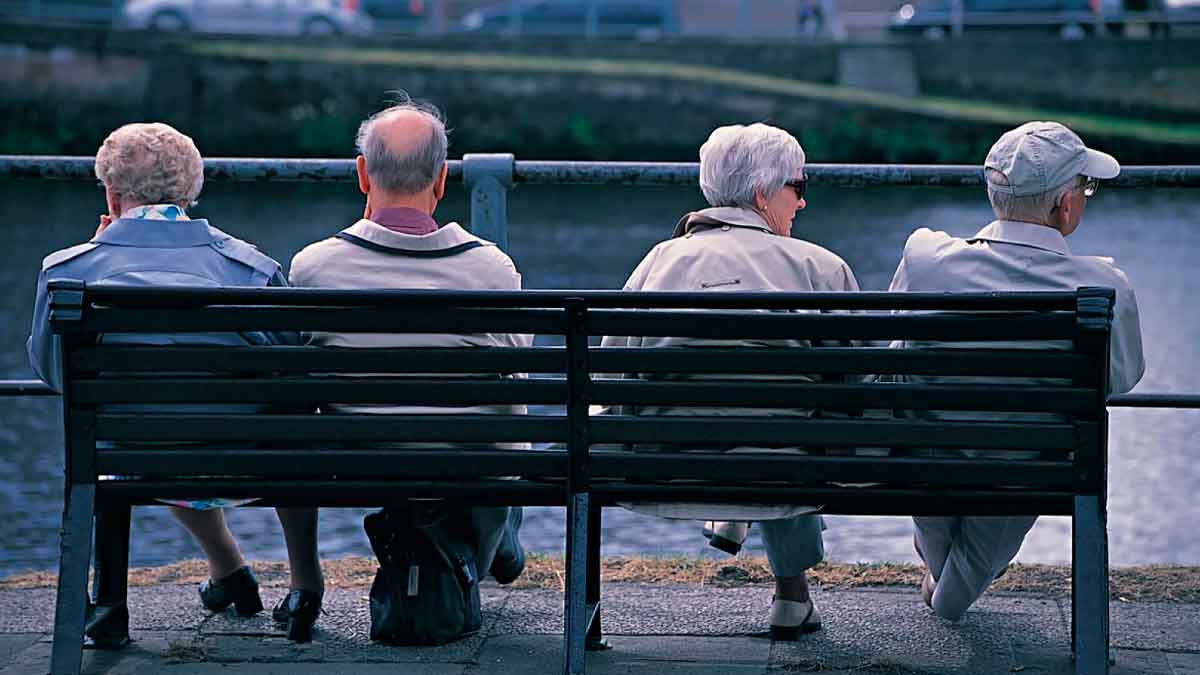 Personas jubiladas sentadas en un banco al aire libre, pensiones 2026 Seguridad Social