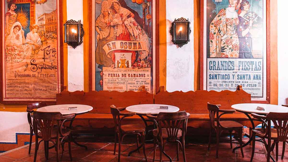 Interior del restaurante El Pimpi en Málaga con carteles antiguos y mesas tradicionales