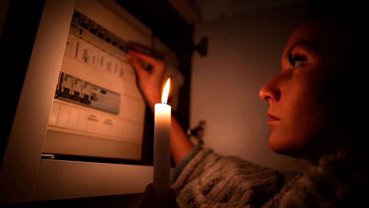 Mujer con vela revisando cuadro eléctrico durante un apagón en Andalucía