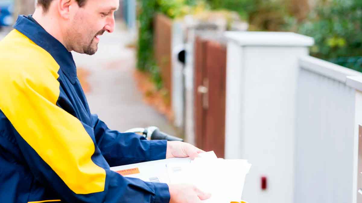 Cartero repartiendo cartas y paquetes en la calle durante su jornada laboral