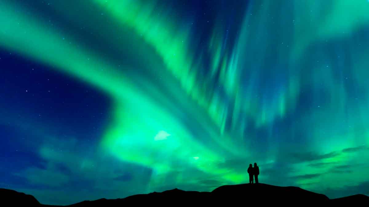 Aurora boreal visible en el cielo nocturno de Andalucía con personas observando el fenómeno natural