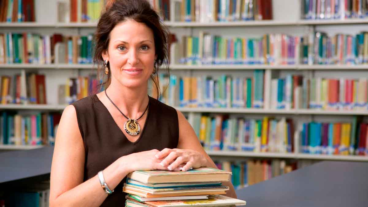 Auxiliar de biblioteca en biblioteca municipal preparando libros para préstamo público