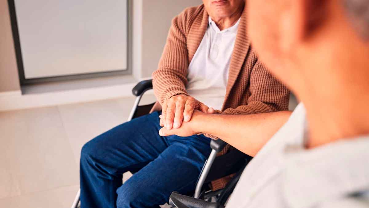 Persona en silla de ruedas recibiendo apoyo, imagen ilustrativa de la ayuda de la Junta de Andalucía para pacientes con ELA