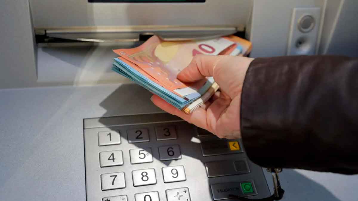 Persona retirando dinero en un cajero tras el adelanto del pago de pensiones de octubre 2025 por Bankinter y Unicaja