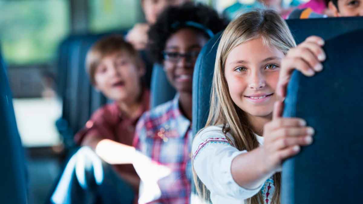 Niños y niñas en autobús escolar representan las becas de 200 euros para transporte del alumnado curso 2025-2026