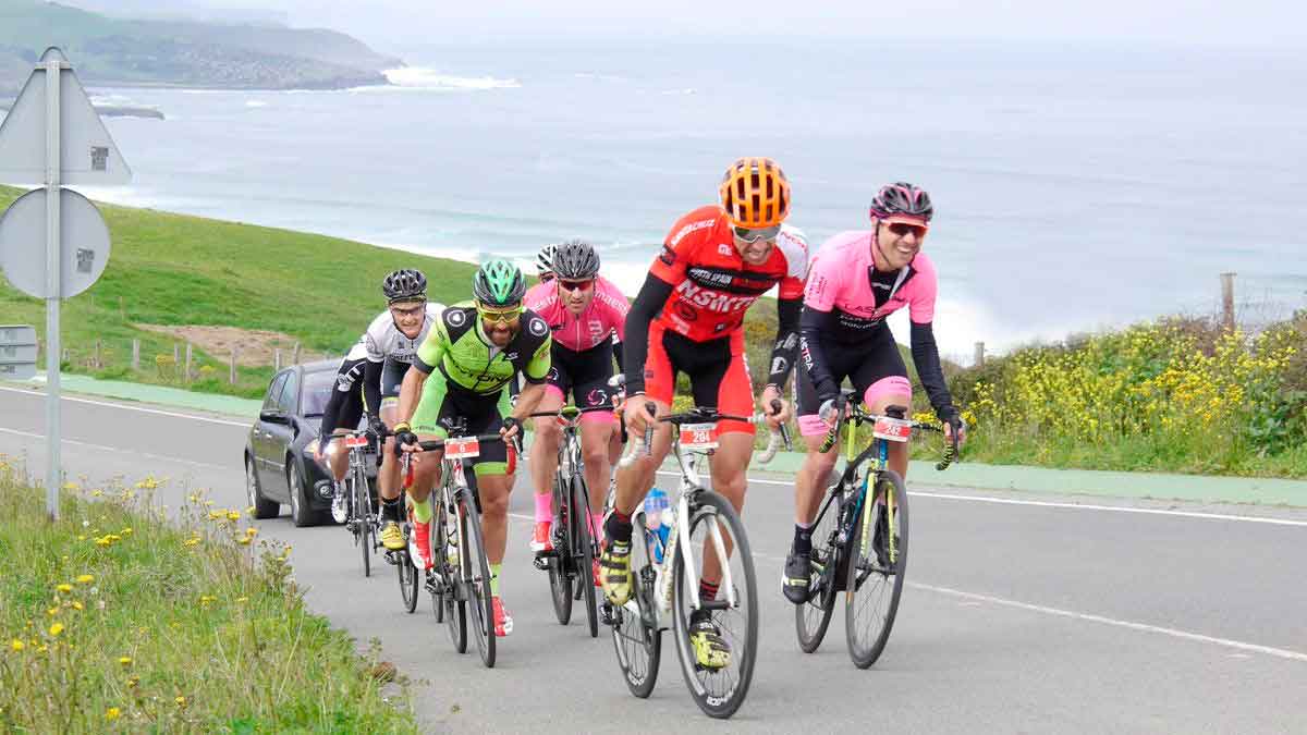 Ciclistas circulando por carretera nacional junto al mar, ejemplo del cambio de arcenes por carriles bici según el BOE