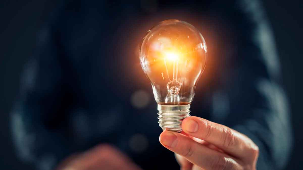 Persona sosteniendo una bombilla encendida que representa el ahorro de energía con el Bono Social Eléctrico 2025