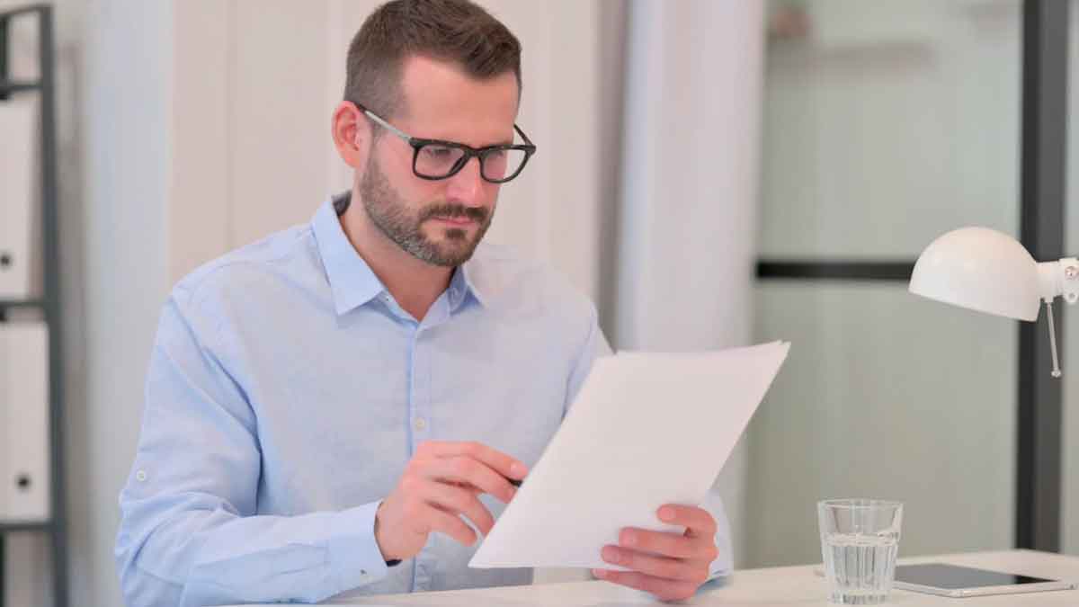 Hombre revisando documentos sobre cotizaciones a la Seguridad Social por reducción de jornada o suspensión de contrato