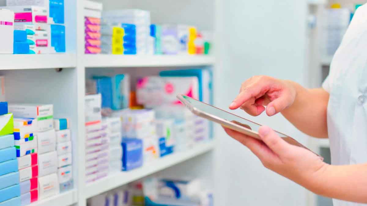 Empleada de farmacia revisando medicamentos con una tableta, relacionado con un despido por falta de título profesional