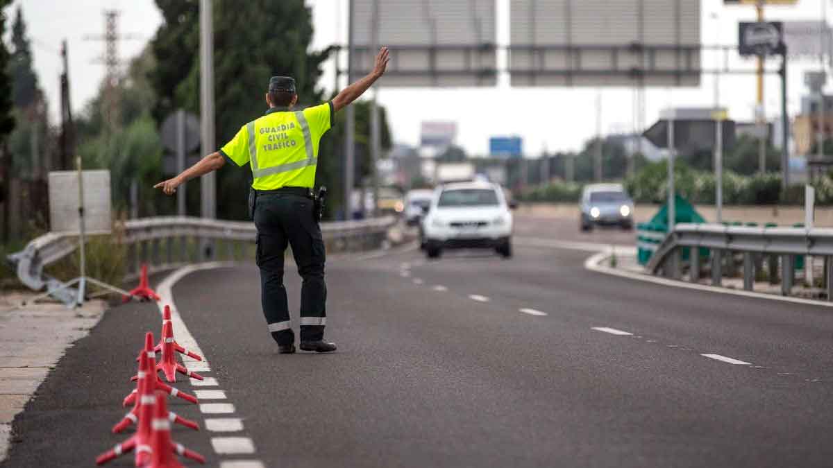 Agente de la Guardia Civil de Tráfico dando el alto a coches en carretera por gestos sancionables según la DGT