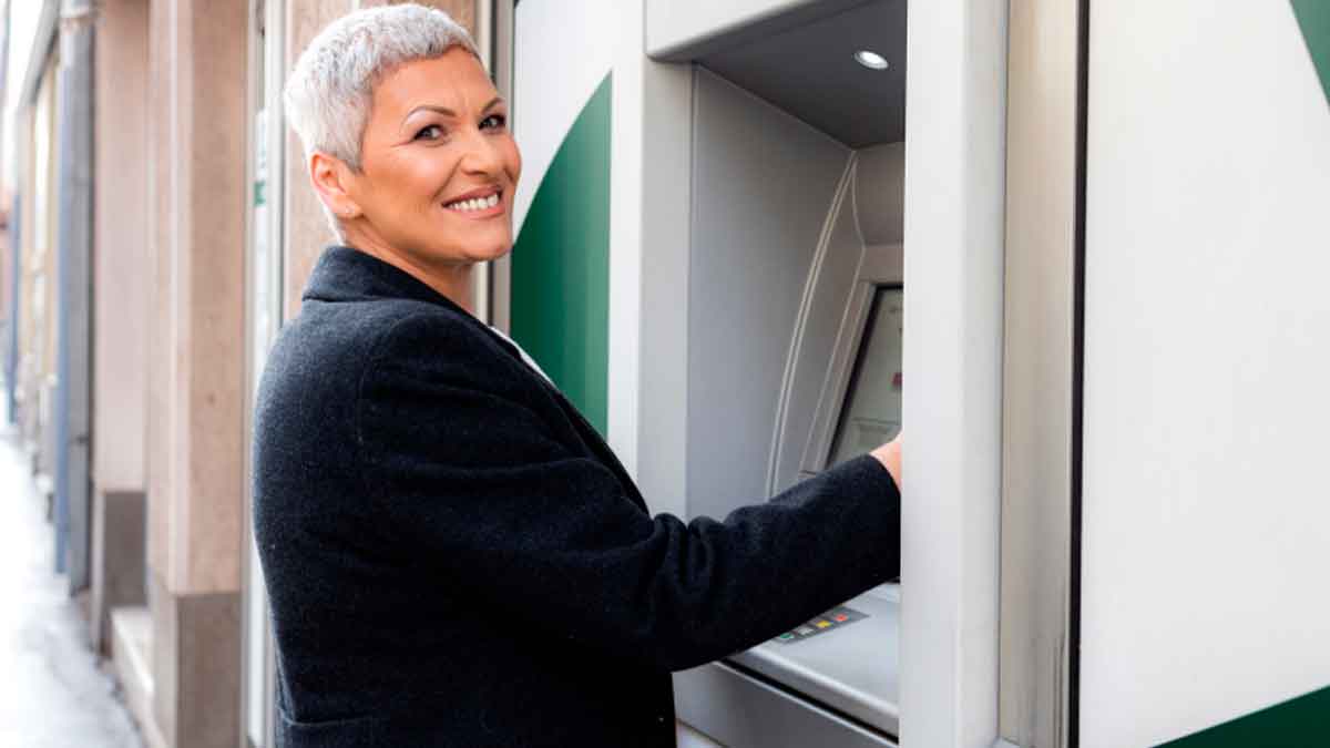 Mujer sacando dinero del cajero tras el ingreso de su pensión en octubre de 2025