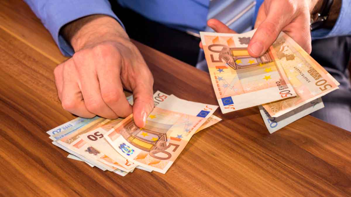 Persona contando billetes de 50 euros sobre una mesa, concepto de pagos en efectivo en empresas y control de Hacienda