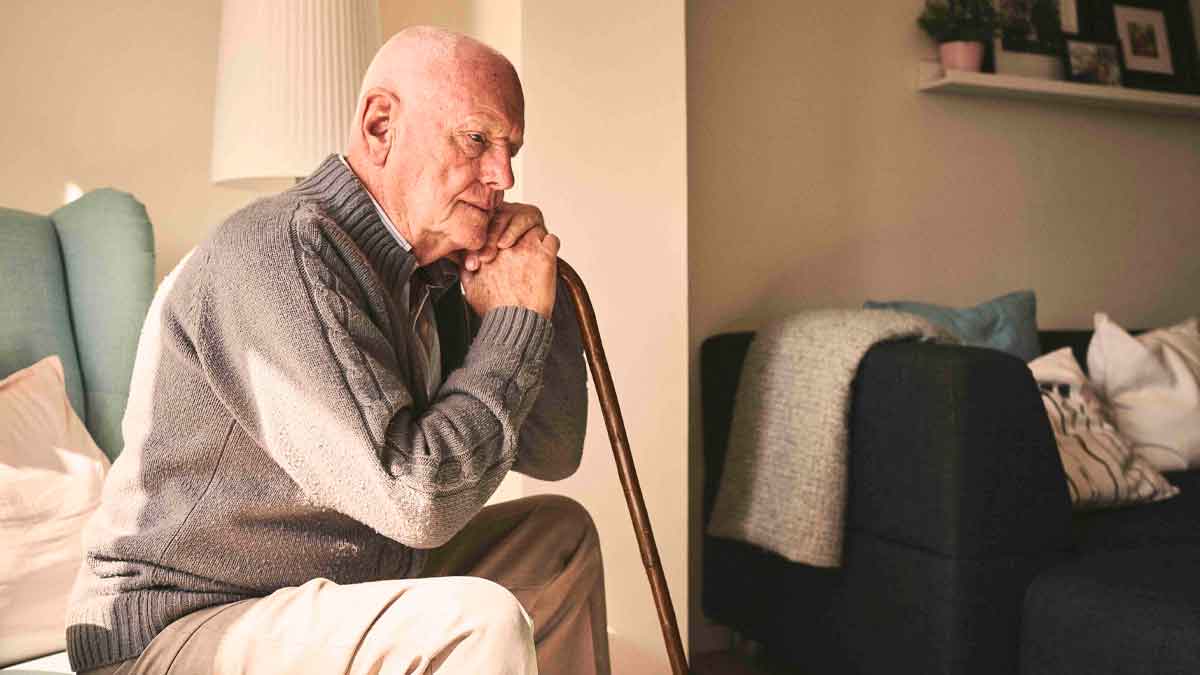 Hombre mayor sentado en casa con bastón por noticia de Hacienda que premia a quienes conviven con personas mayores