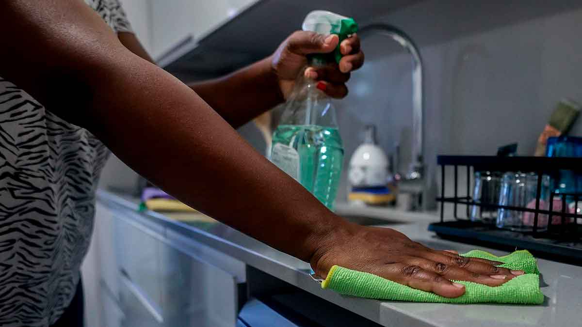 Empleada del hogar limpiando cocina, riesgo de multa por no estar dada de alta en Seguridad Social