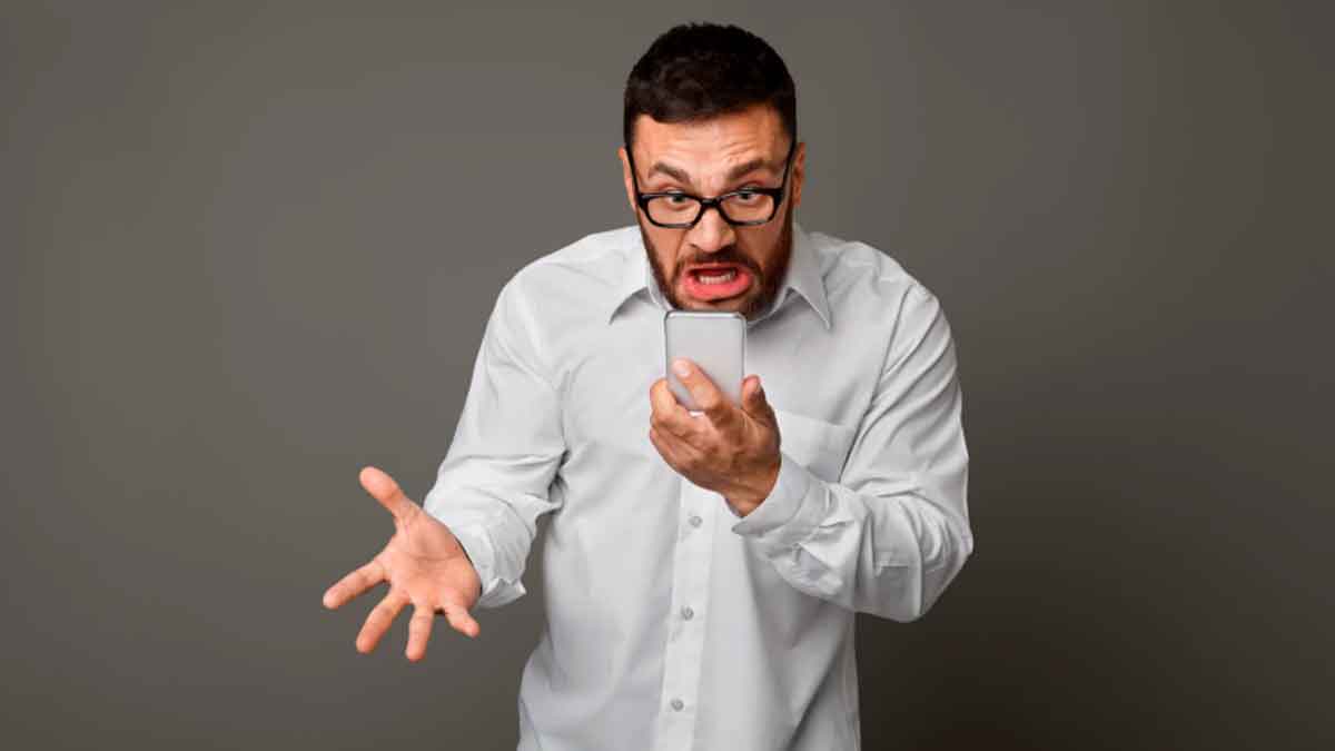 Hombre enfadado mirando su móvil tras descubrir multas pendientes con la DGT o Hacienda