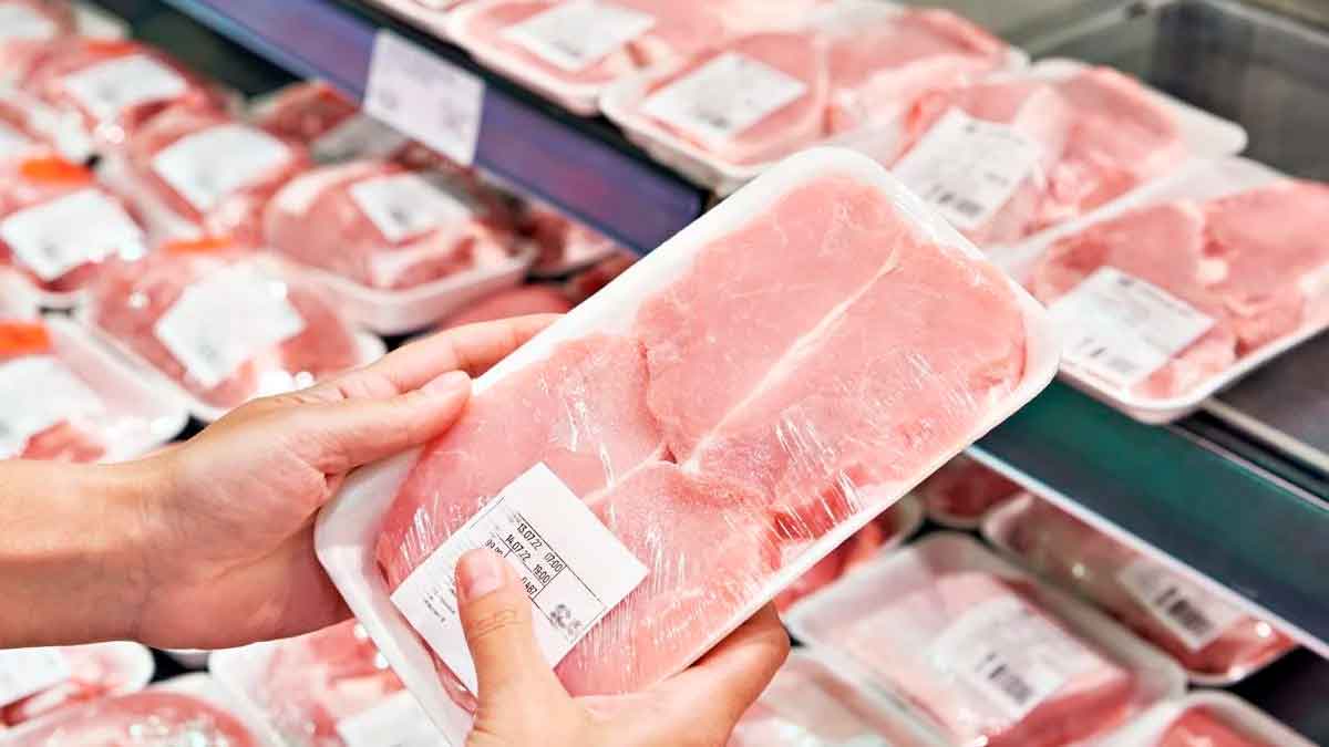 Persona sosteniendo bandeja de carne envasada etiquetada como extratierna en un supermercado