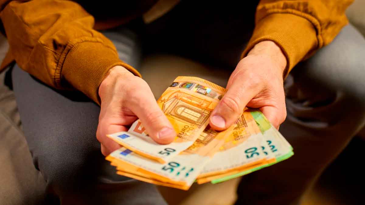 Manos de pensionista contando billetes de euro tras recibir el complemento de la Seguridad Social