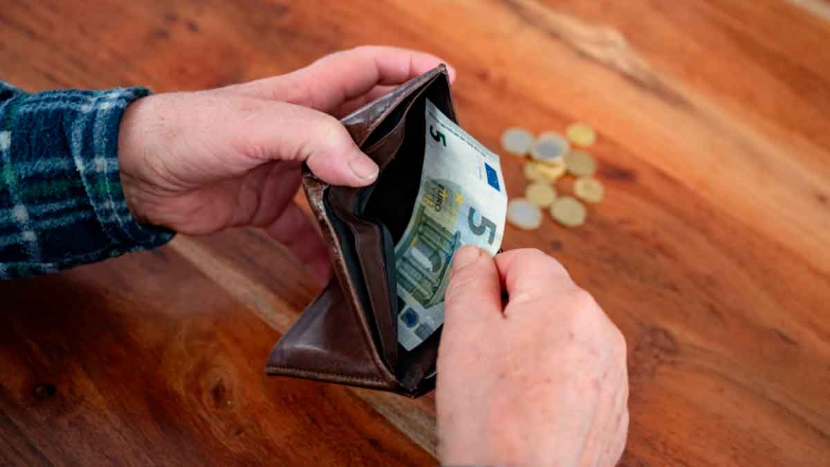 Manos de pensionista con cartera y pocos billetes por no recibir la paga extra de Navidad 2025 según la Seguridad Social