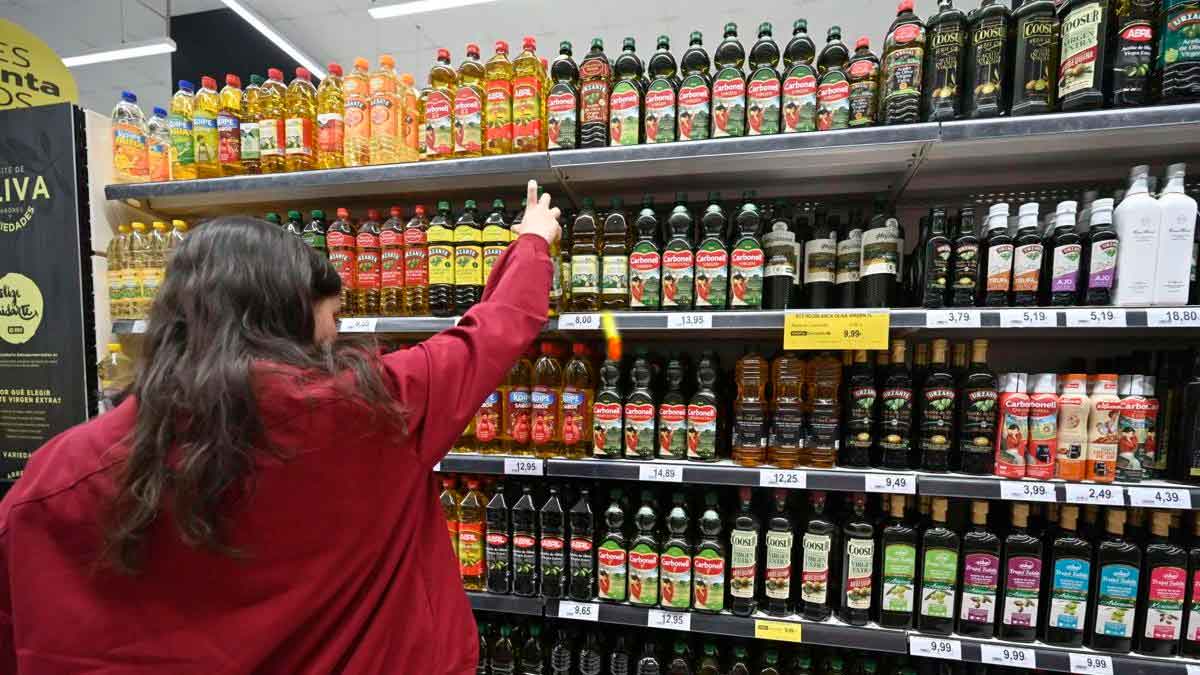 Persona eligiendo aceite de oliva en un supermercado con precios estables antes de la campaña de Navidad