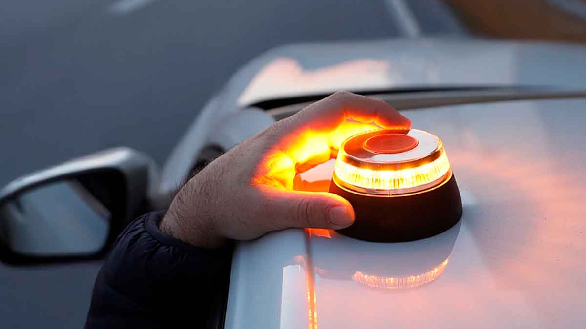 Conductor coloca una luz de emergencia V16 sobre su coche, obligatoria por la DGT desde 2026