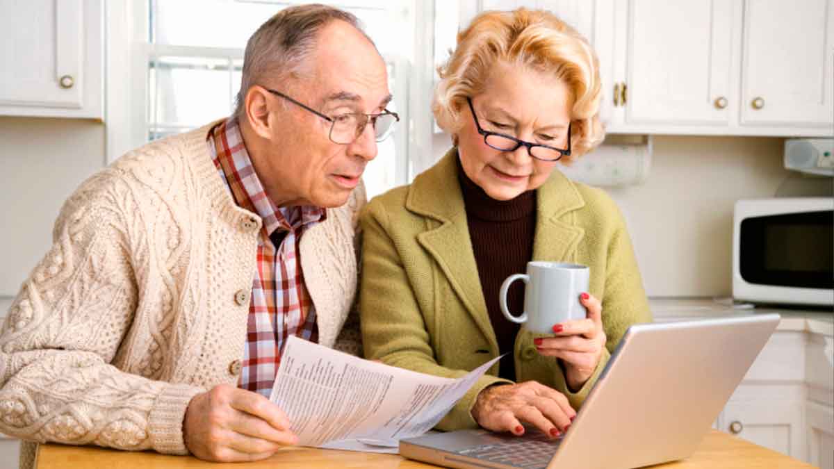Pareja de jubilados revisando en el ordenador qué mes conviene jubilarse para conseguir una pensión más alta