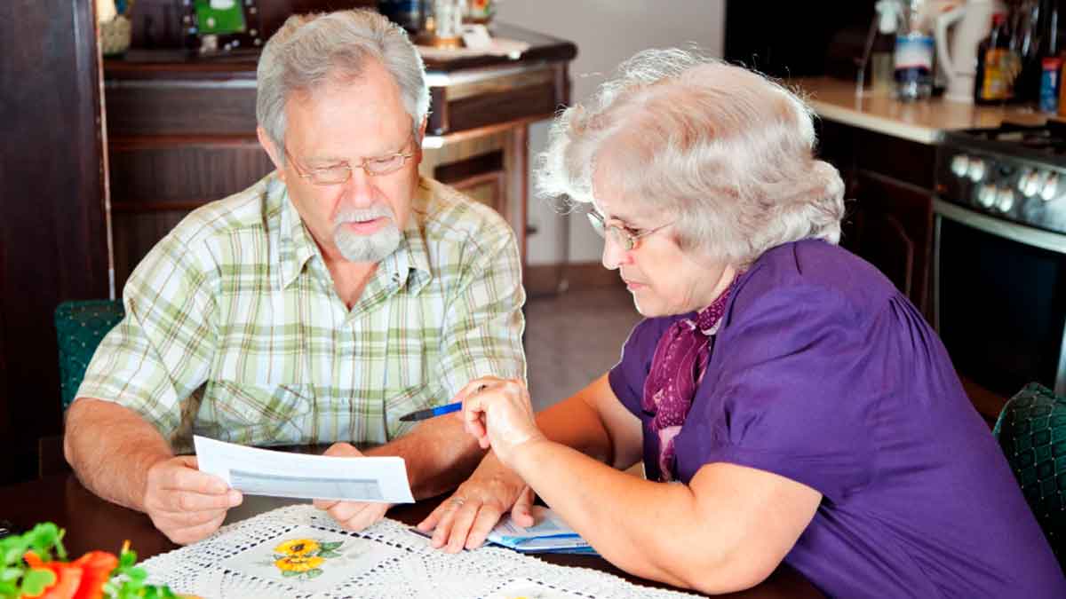 personas mayores revisando documentos sobre su pensión y la Paga extra de Navidad de la Seguridad Social 2025