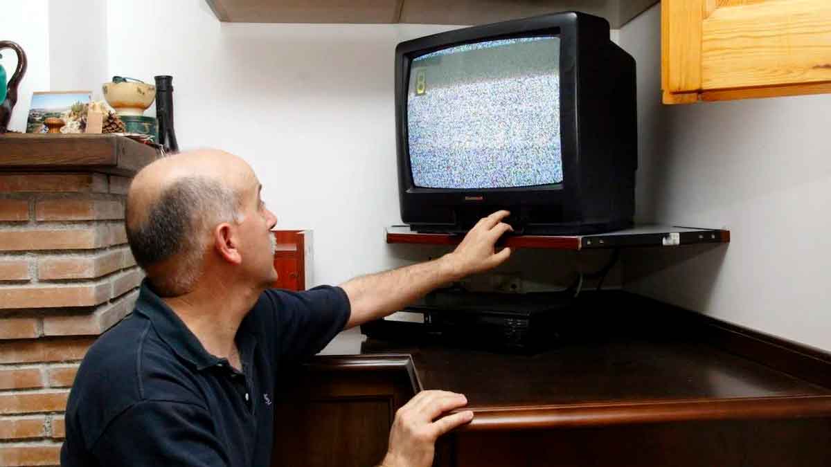 Hombre ajustando un televisor antiguo con señal de TDT sin antena