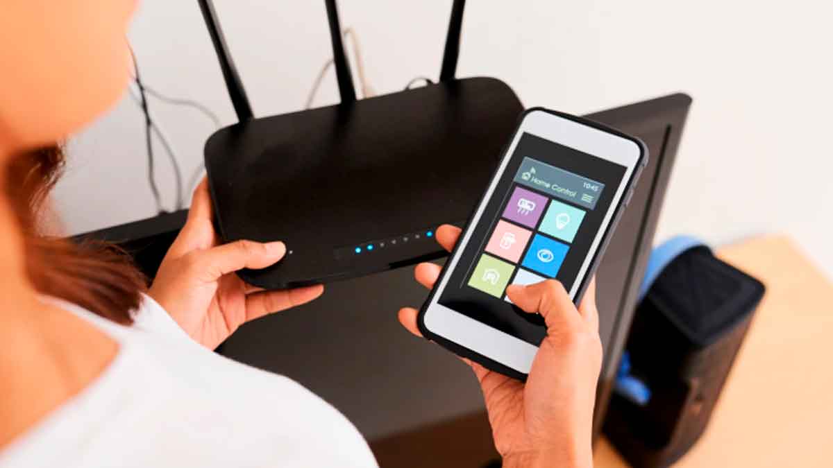 Persona comprobando el router y el móvil para saber si un vecino usa su WiFi sin permiso