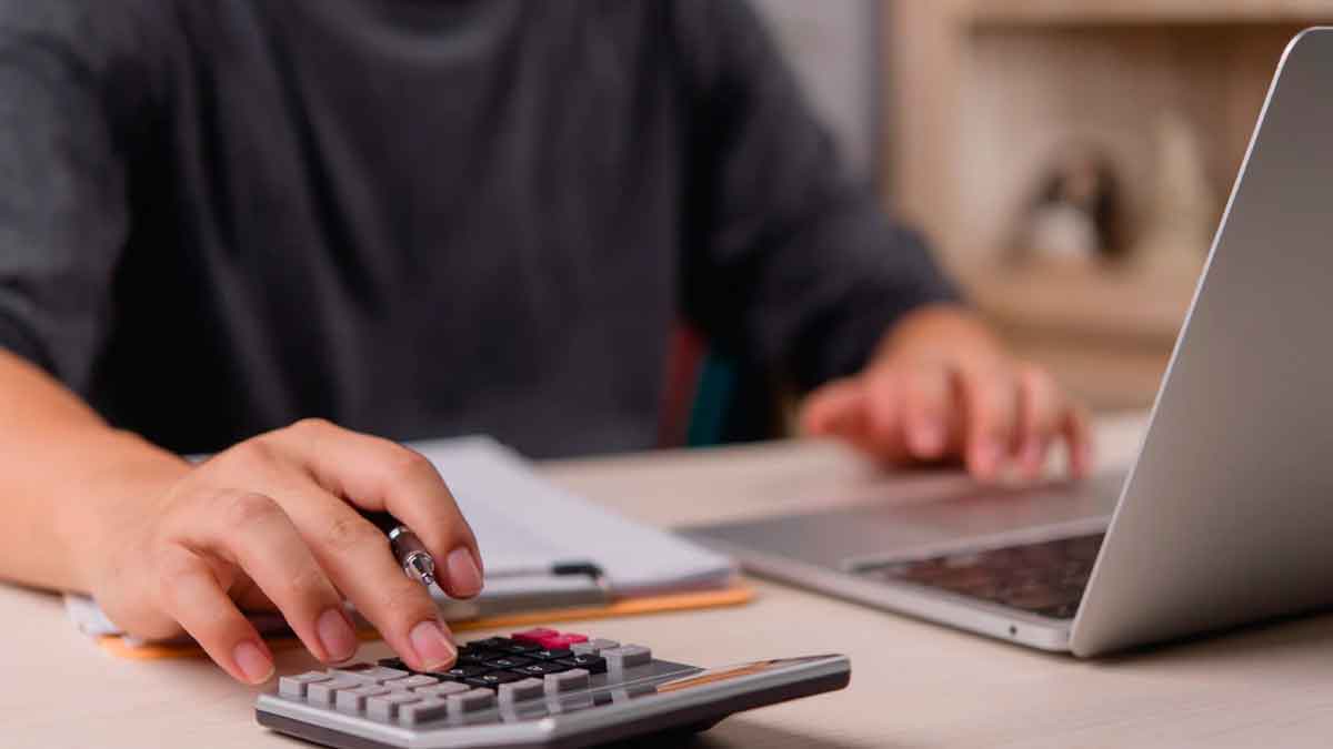 Persona utilizando calculadora y ordenador para revisar gastos y ahorrar en la declaración de la Renta 2025