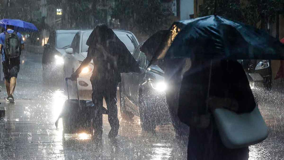 Personas caminando bajo intensa lluvia en Andalucía durante la alerta amarilla activada por la AEMET por riesgo de tormentas y tornados