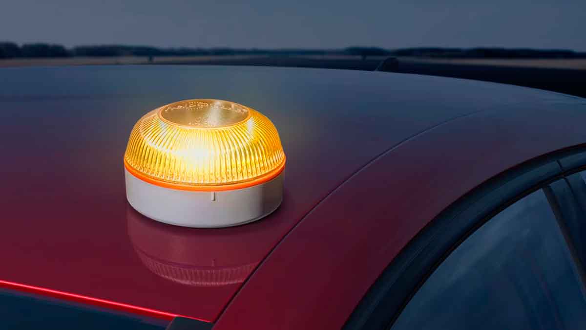 Baliza V16 encendida sobre el techo de un vehículo para señalizar una emergencia en carretera