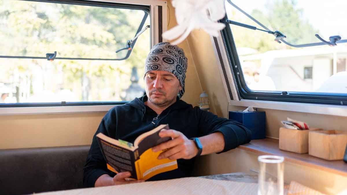 Hombre leyendo un libro en el interior de una autocaravana durante su día a día