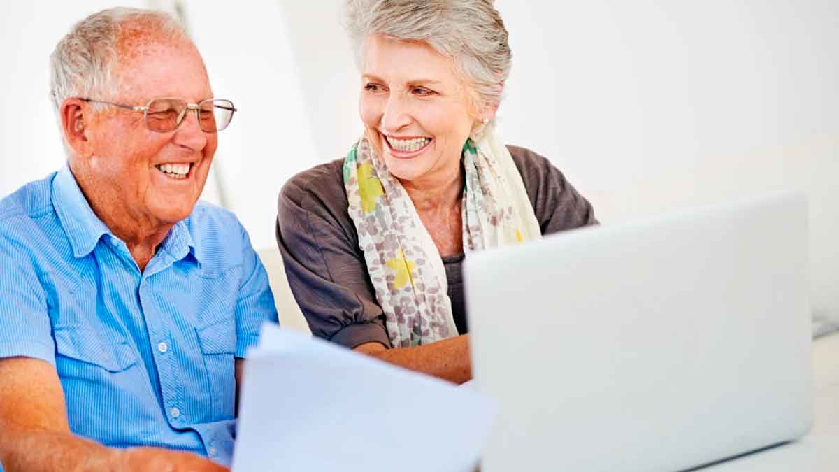 Pareja de personas mayores revisando trámites de la Seguridad Social en un ordenador