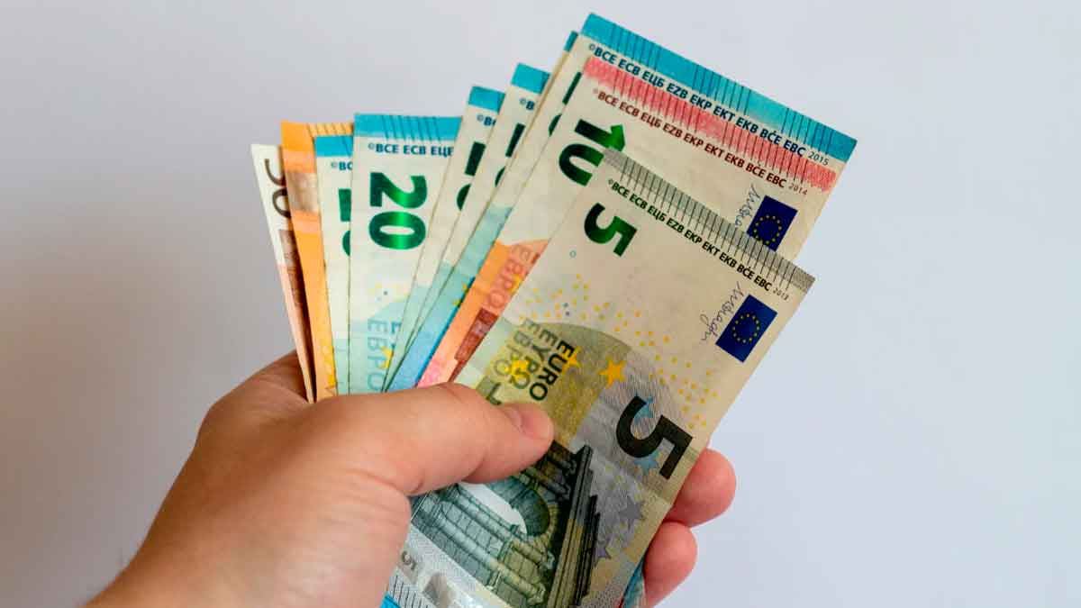 Mano sosteniendo billetes de euro para ilustrar ayuda social urgente de hasta 2.999 euros