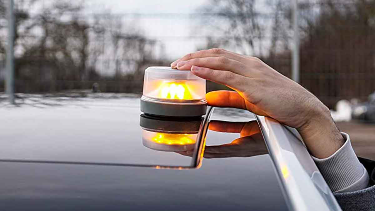 Mano colocando una baliza V16 conectada y homologada por la DGT sobre el techo de un coche