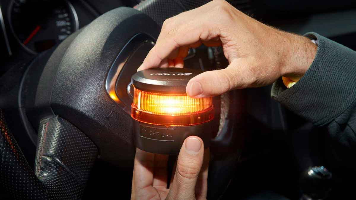 Conductor colocando una baliza V16 encendida en el interior del vehículo