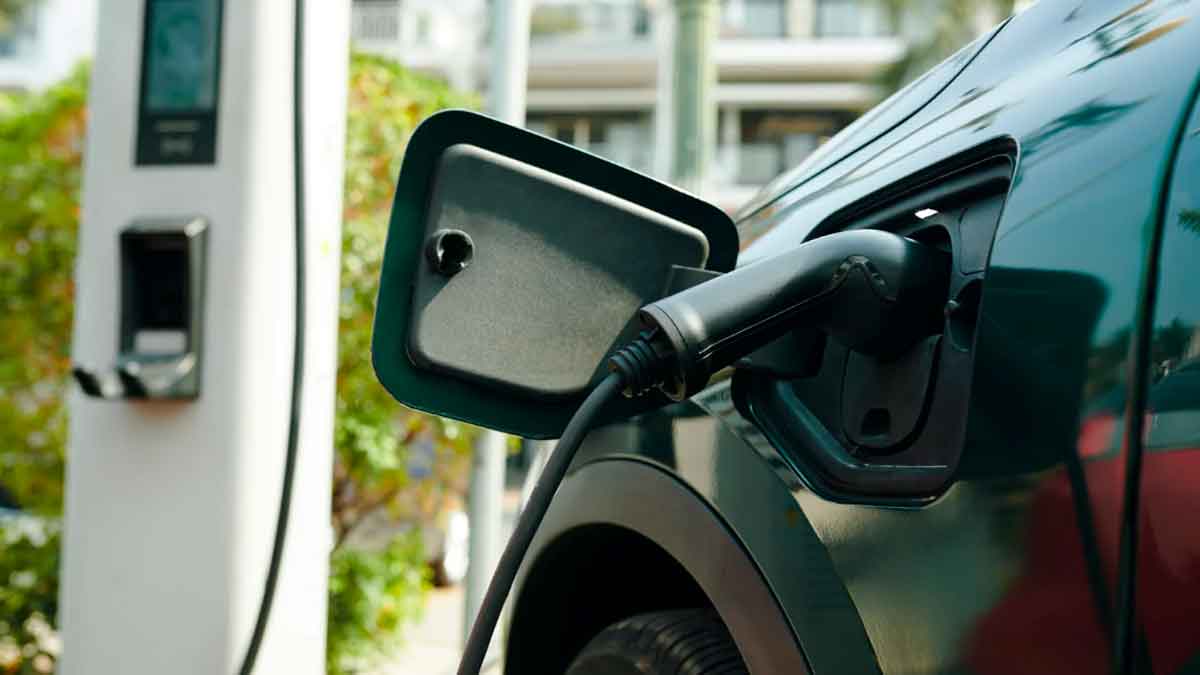 Coche eléctrico cargando su batería en un punto de recarga según recomendaciones de la OCU