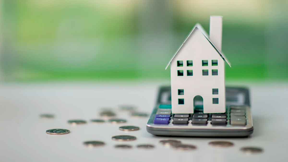 Casa en miniatura sobre una calculadora con monedas alrededor, simbolizando el cálculo de hipotecas fijas