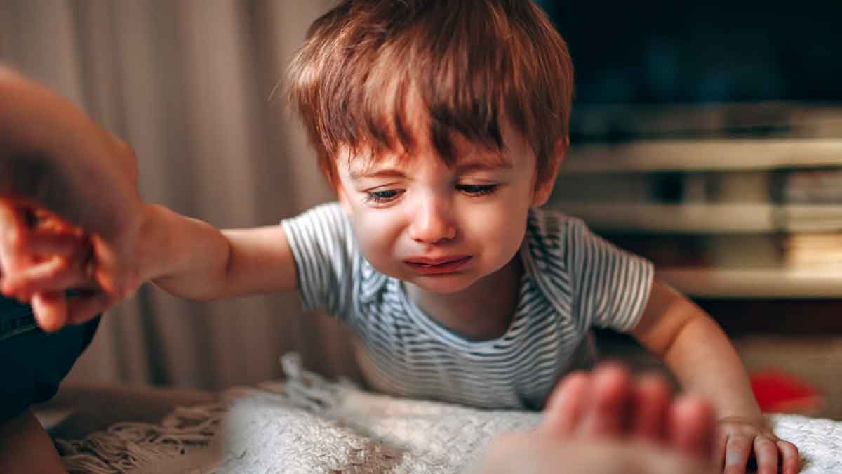 Niño pequeño llorando mientras un adulto le sostiene la mano en un entorno doméstico