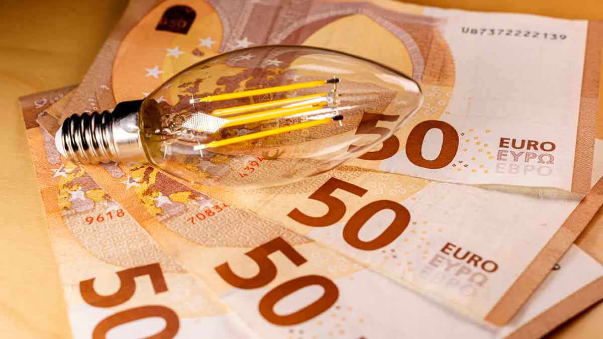 Bombilla sobre billetes de 50 euros simbolizando el ahorro en la factura de la luz