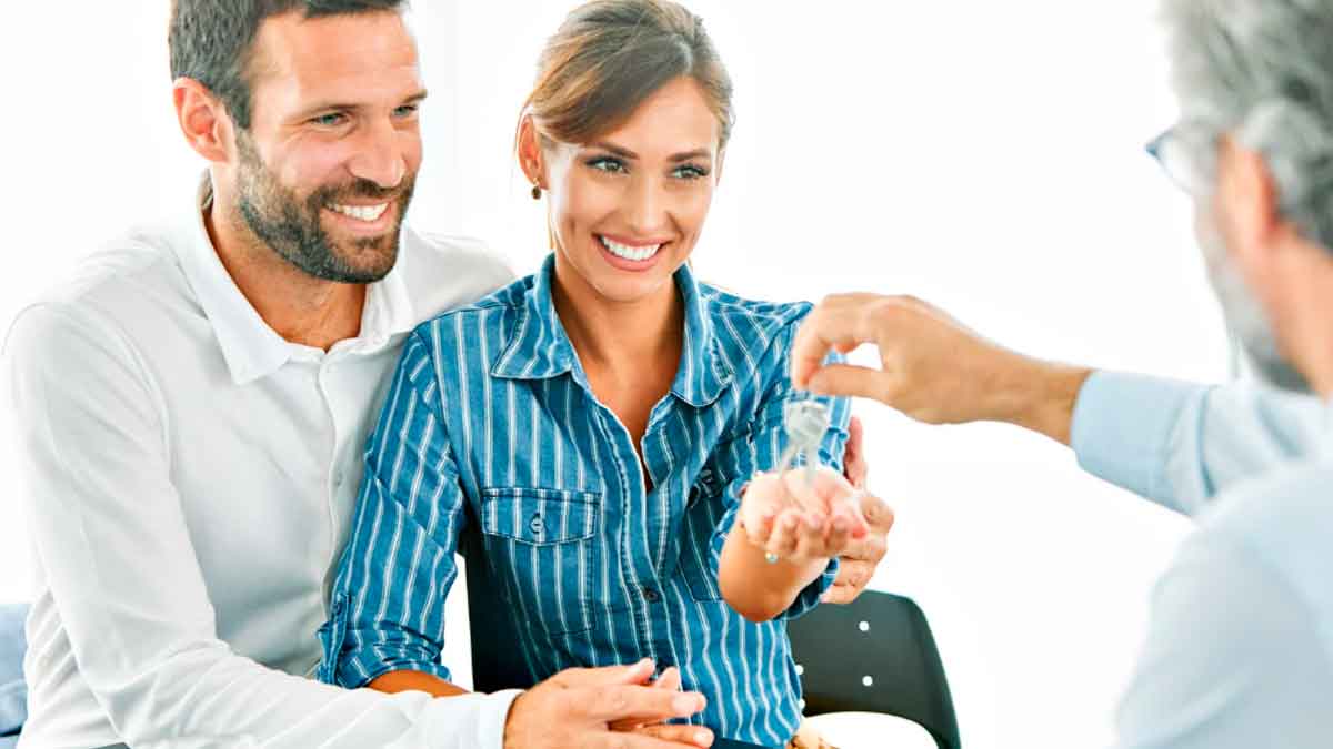 Pareja feliz recibiendo las llaves de su nueva vivienda tras decidir comprar casa en 2025