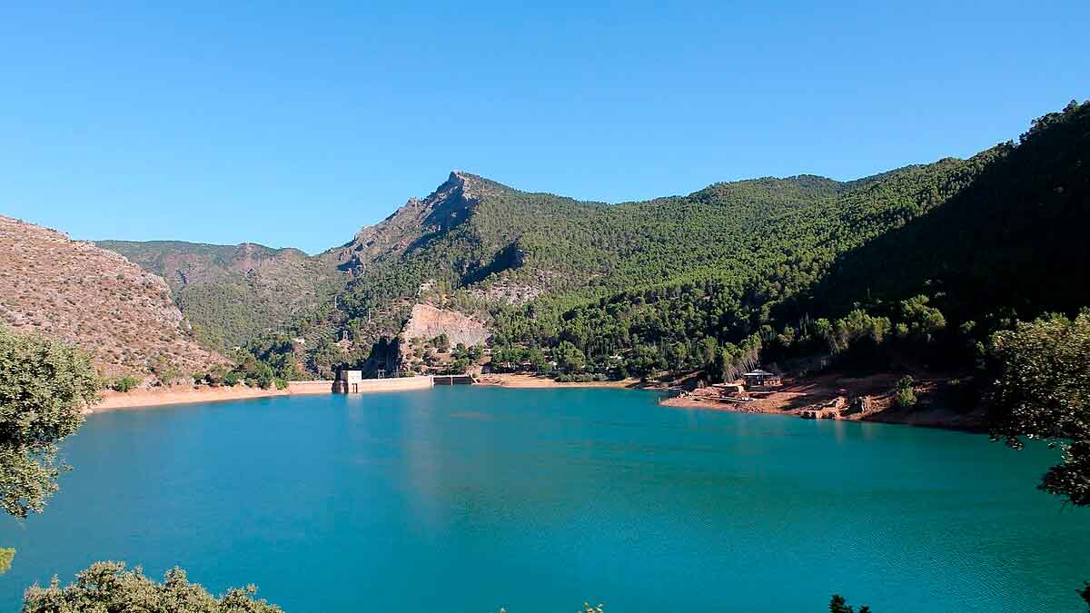 Embalse andaluz con aumento de reservas de agua rodeado de montañas y vegetación