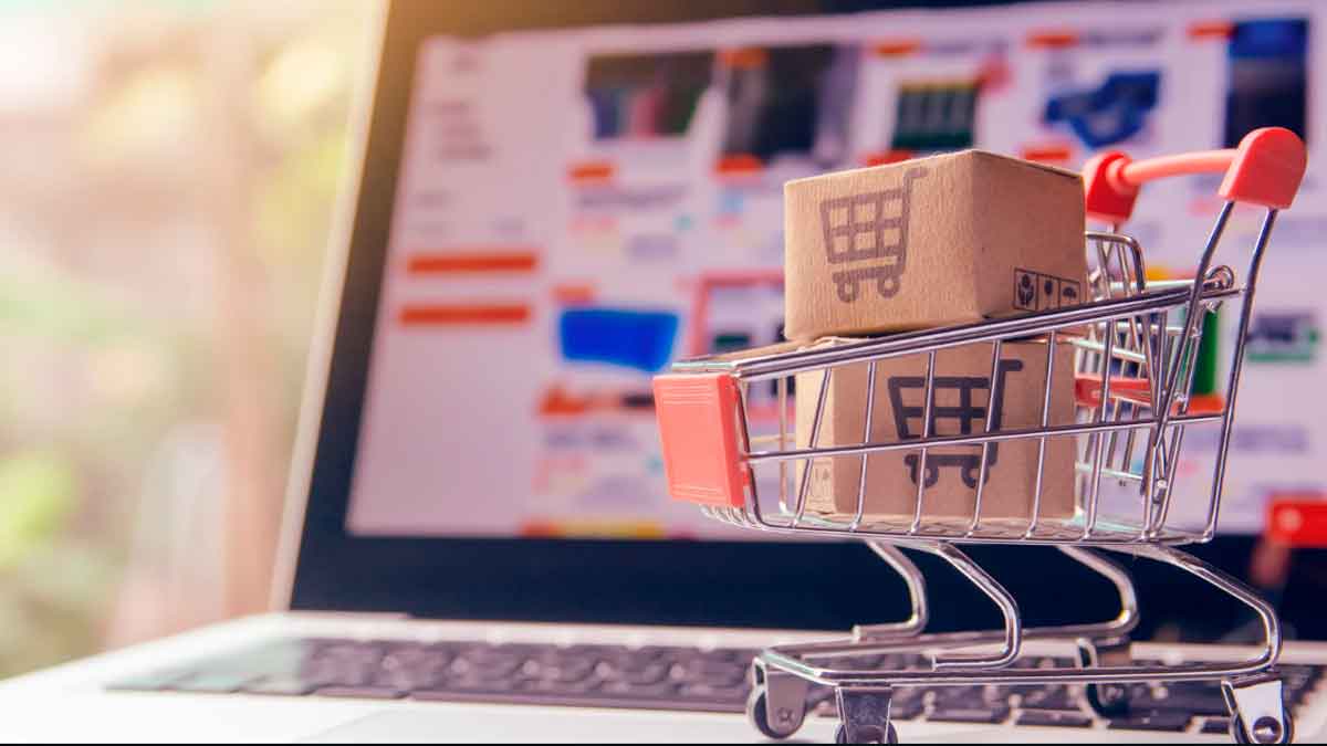 Carrito de compras con paquetes frente a un ordenador representando el comercio online en el Black Friday