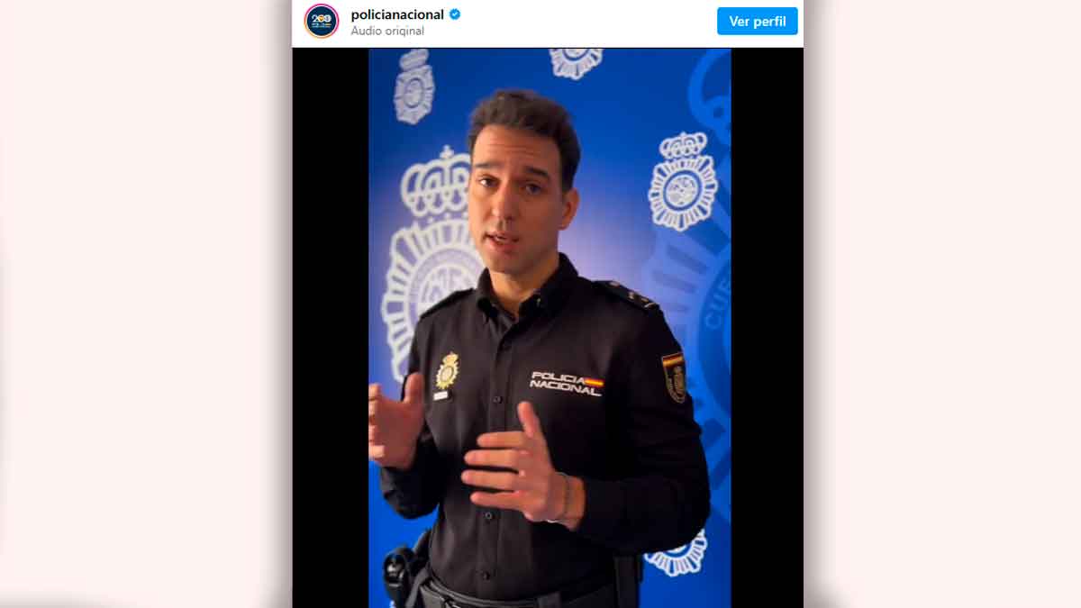 Agente de la Policía Nacional explicando la estafa de la voz clonada frente a un fondo institucional azul
