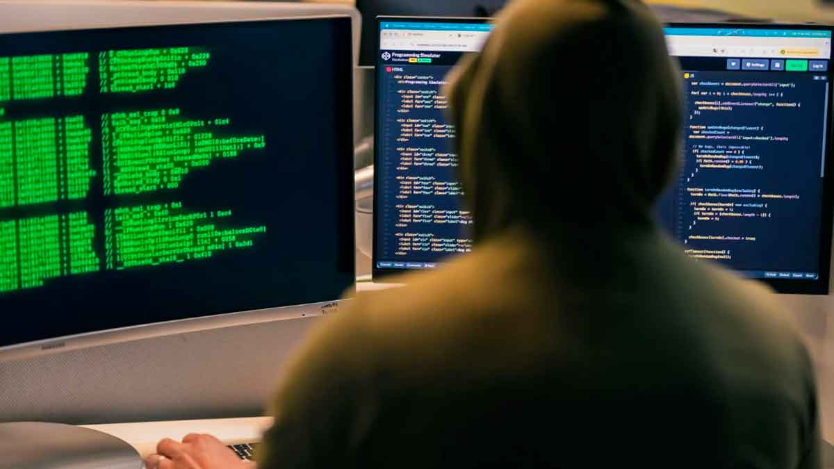 Persona frente a ordenadores con código que representa estafas online con inteligencia artificial